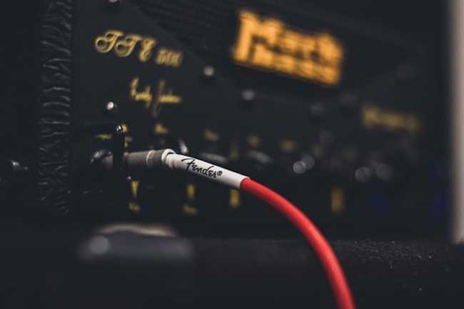 Closeup image of a Fender branded electric guitar cable hooked into an amp